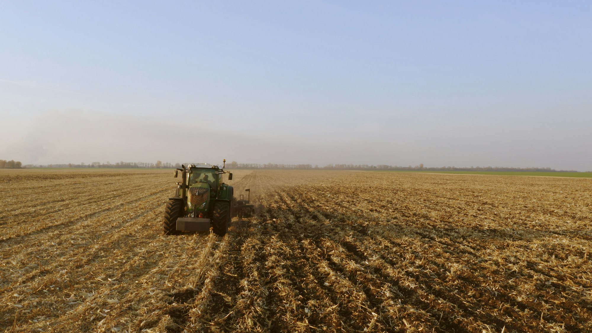 Green tractor working on field.